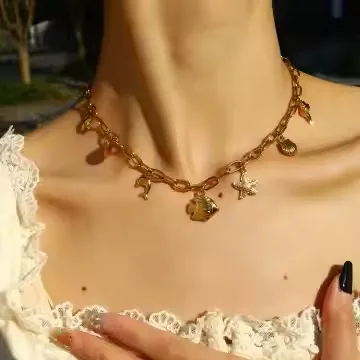 Collier breloque océan en acier inoxydable, collier qui fait du bruit avec pendentifs : étoile de mère, coquillages et dauphin. Collier portée par une femme