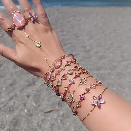 Plusieurs bracelets, bagues et une chaine de main en acier inoxydable portée par une femme sur une plage